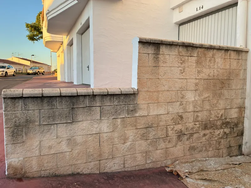 Muro de bloques de hormigón junto a un garaje antes de pintarlo, manchado y con el bloque a la vista