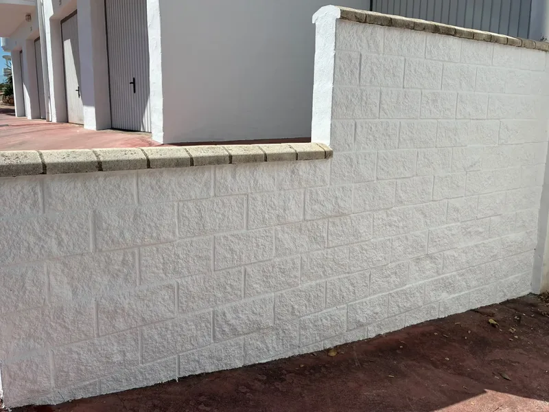 El mismo muro de bloques pintado en blanco por Pinturas hermanos Carvajal, con la albardilla de piedra tal cual